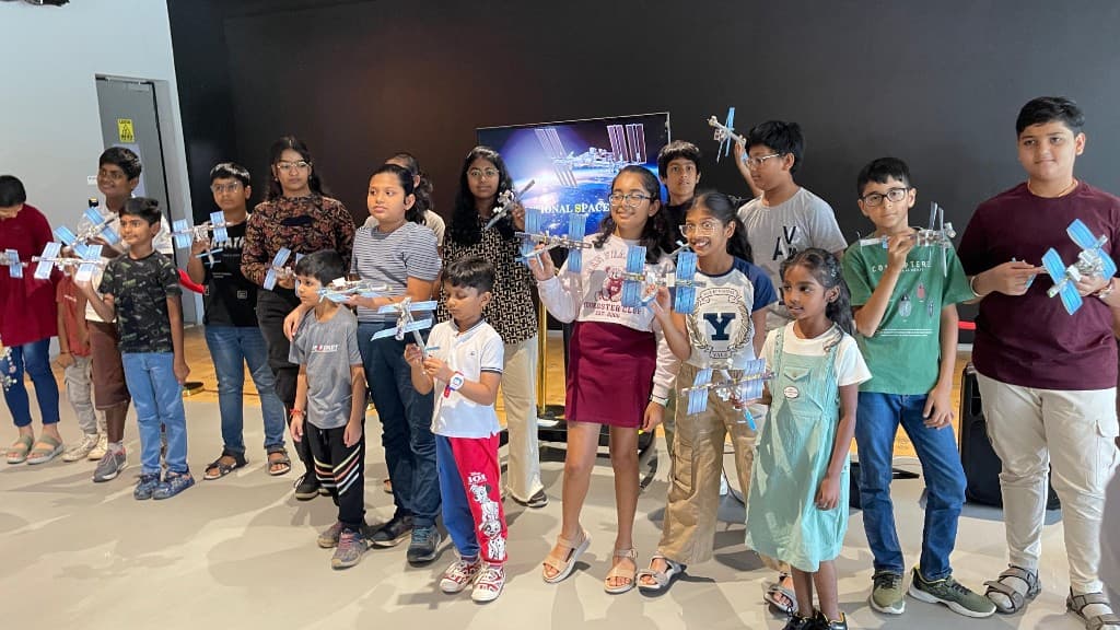 A group of children lined up with model satellites