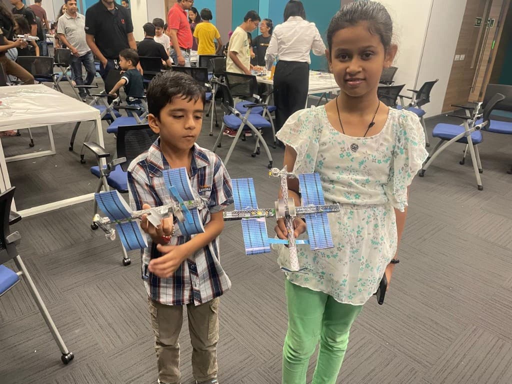 Two children holding completed space-station models